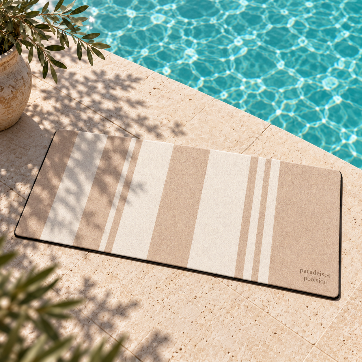 Santorini Sand striped poolside mat laid on pale stone coping beside a sunlit pool